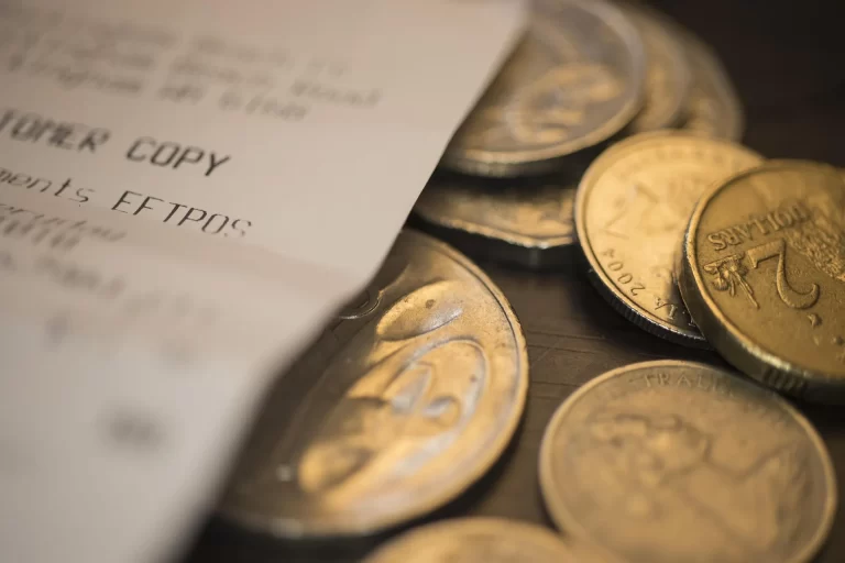 Bonnetje en munten als symbool voor zakelijke kosten en belastingaftrek bij werken vanuit huis.